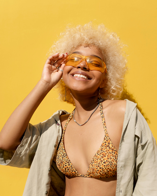 A woman smiling in yellow-tinted sunglasses against a yellow background, illustrating the esteem effect on brand perception